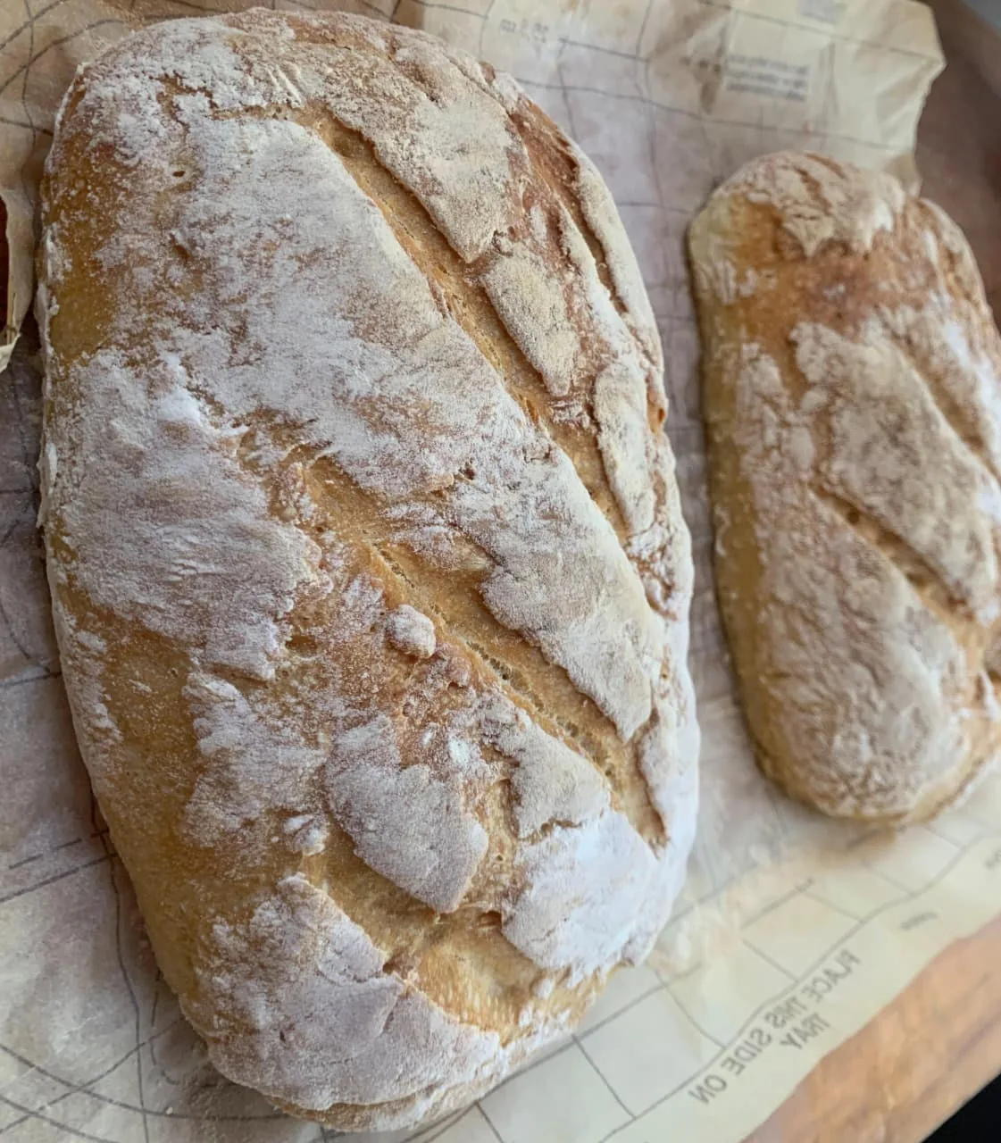 Two rustic loaves cooling on baking paper