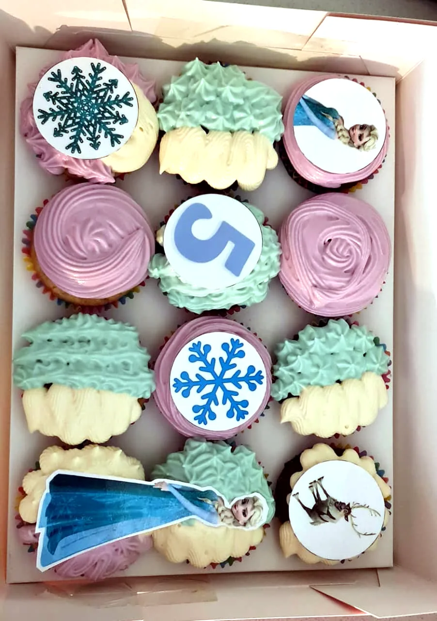 Box of winter-themed birthday cupcakes with snowflake and number five toppers