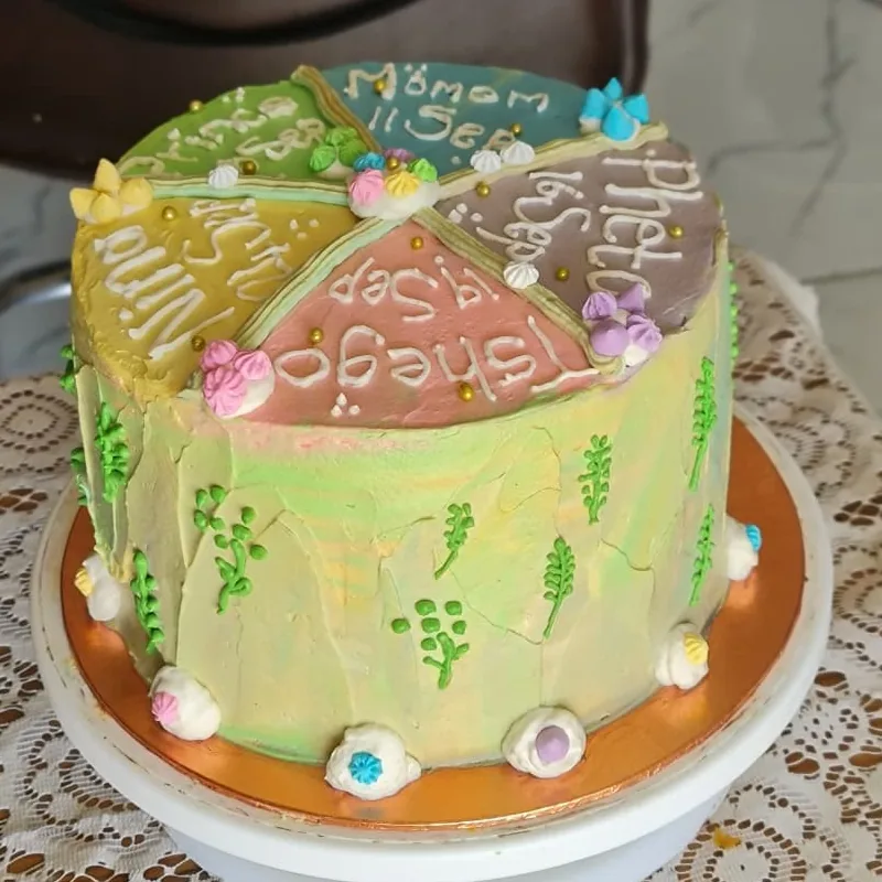 Tall pastel buttercream cake with hand-piped names for several family birthdays