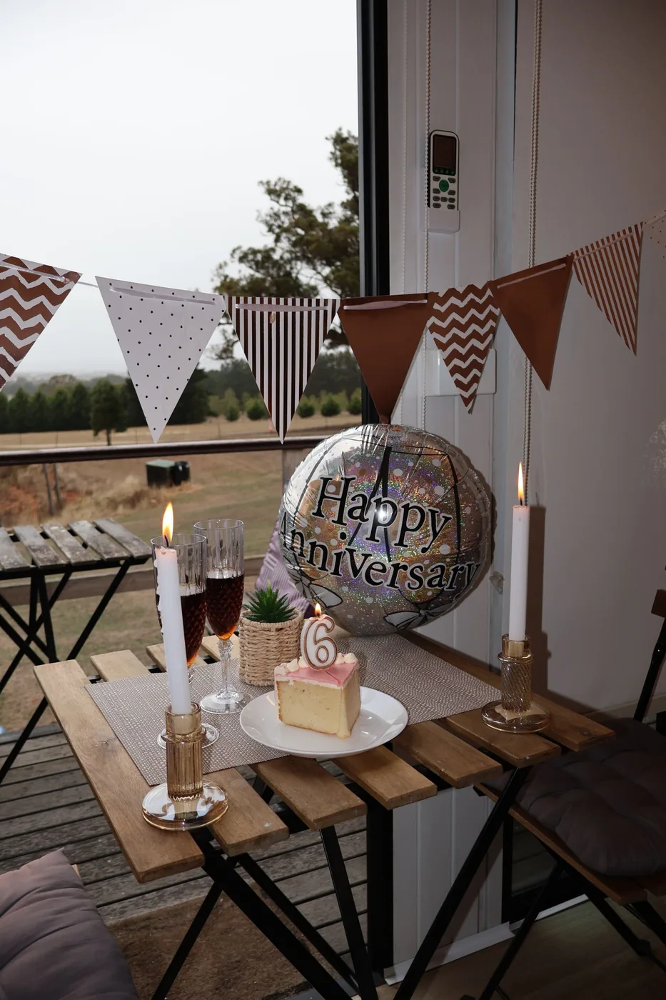 Small anniversary table at home with candles, bunting and a slice of cake