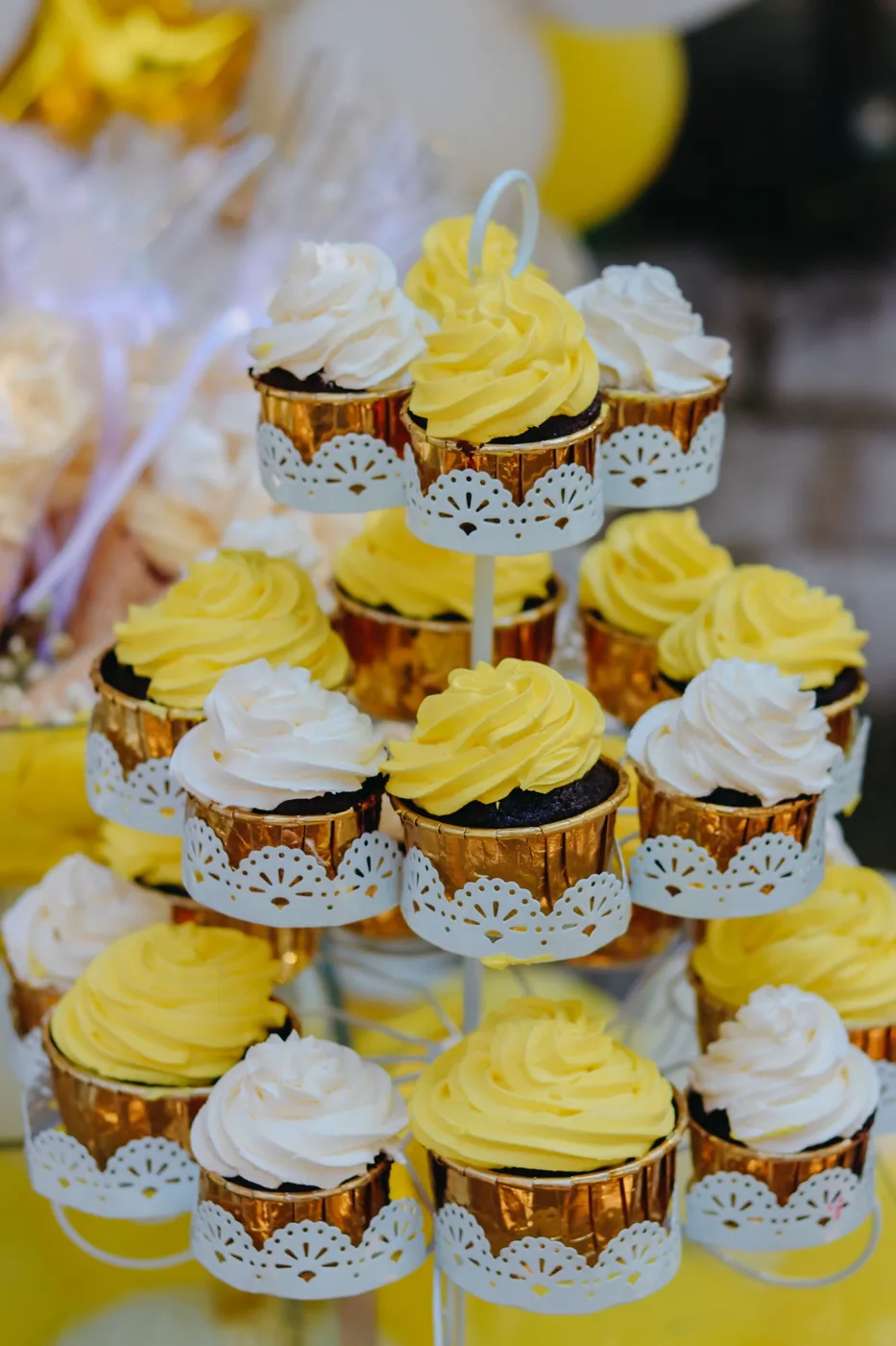 Tower of cupcakes in lace wrappers with yellow and white frosting