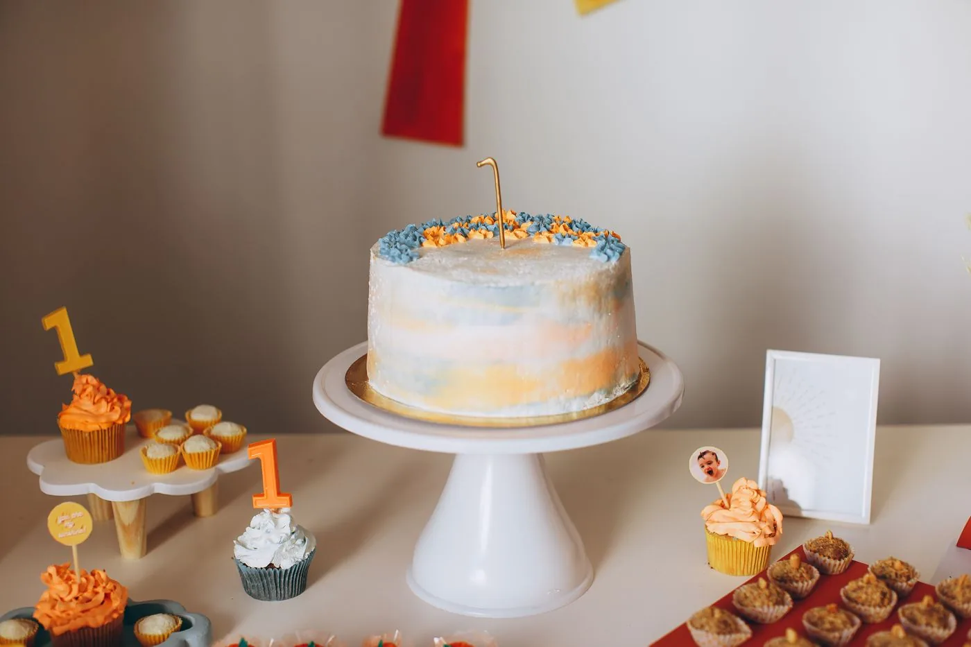 First birthday cake on a stand with cupcakes and treats