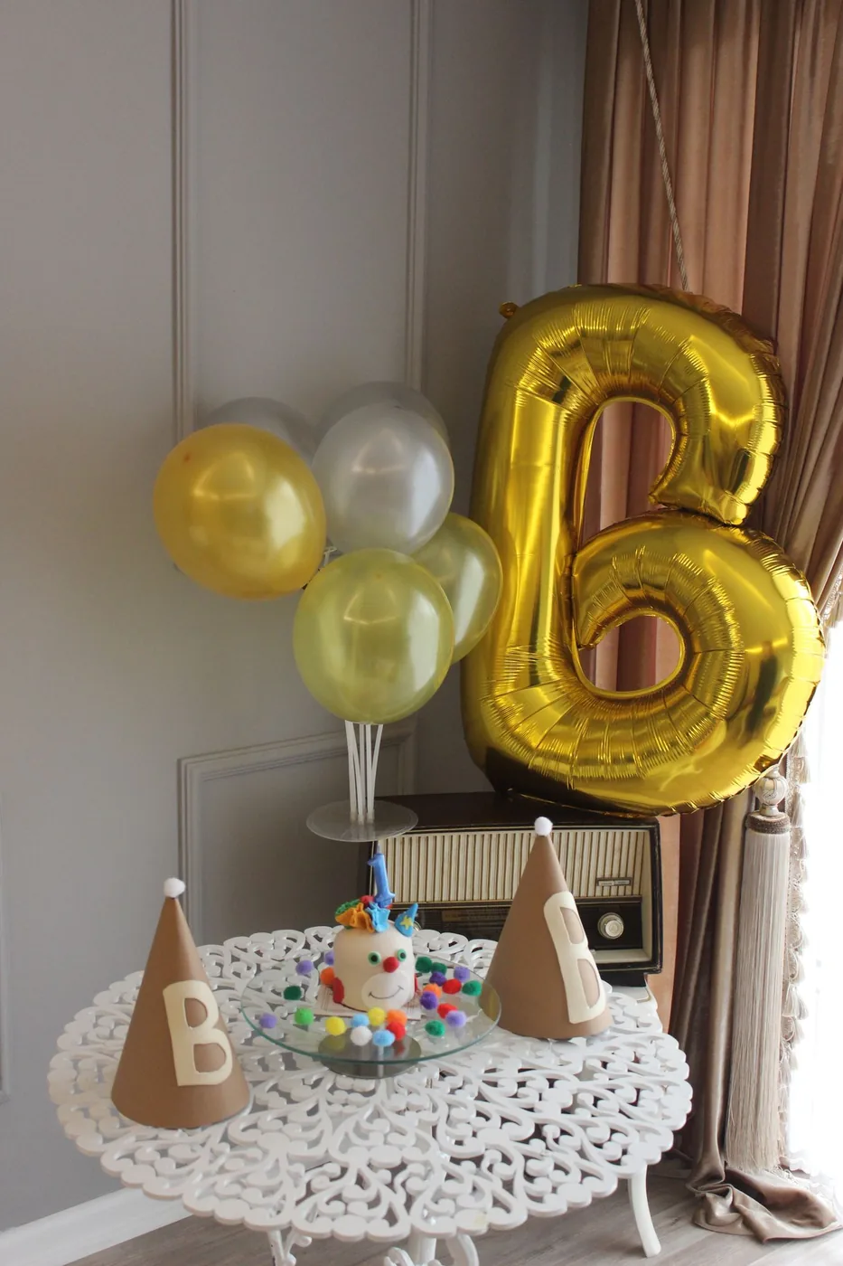Small party table in a home corner with balloons and a mini cake